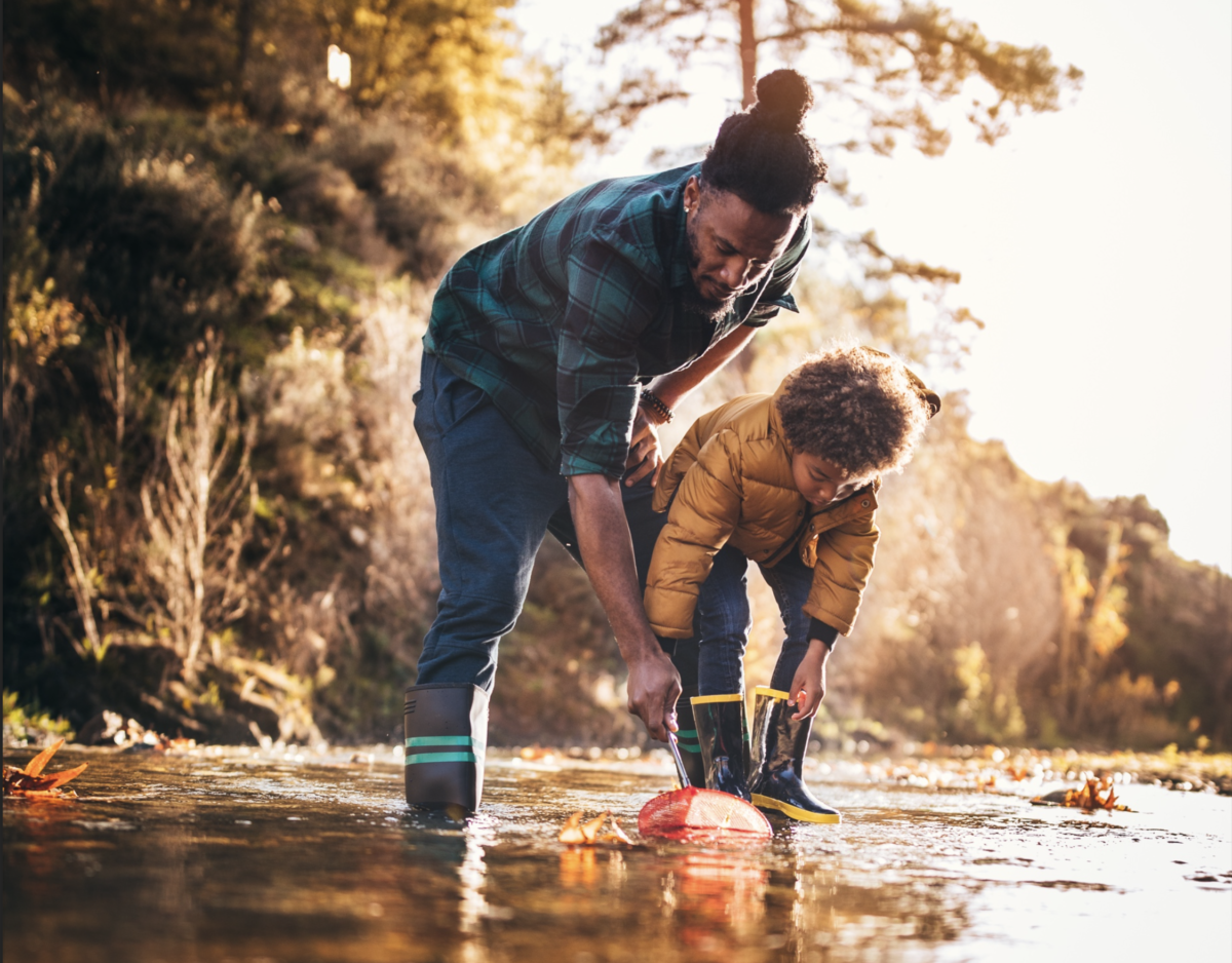 man and child playing in shallow water in the fall